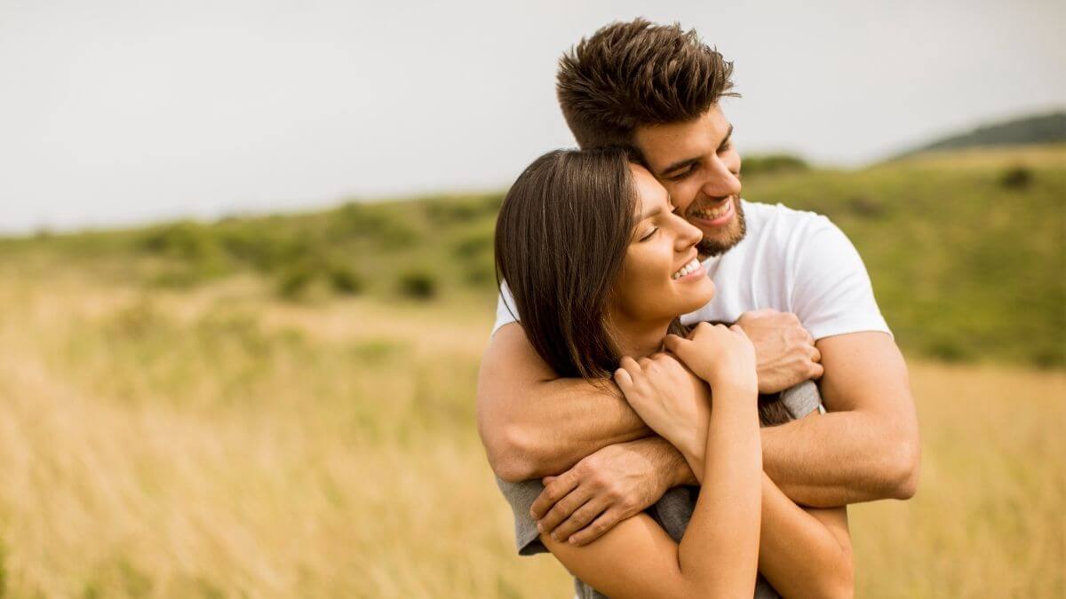 A couple embracing in an open field at sunset