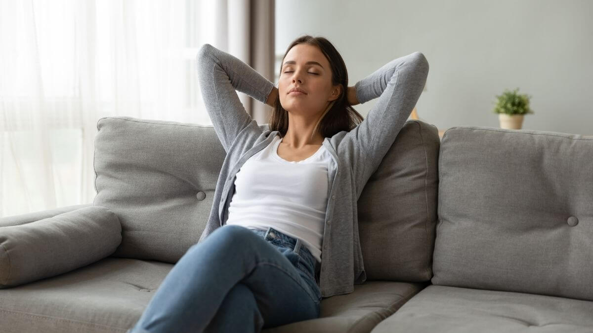 A woman resting peacefully on a sofa with her eyes closed
